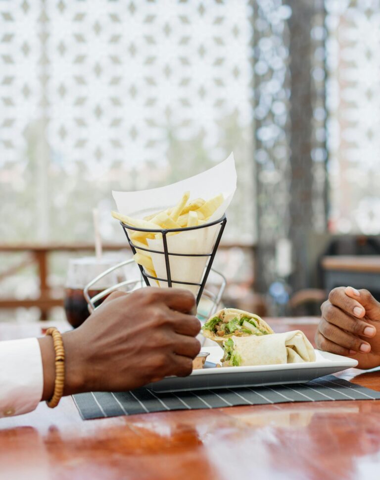 African couple dining outdoors with French fries and wrap in Accra, Ghana.