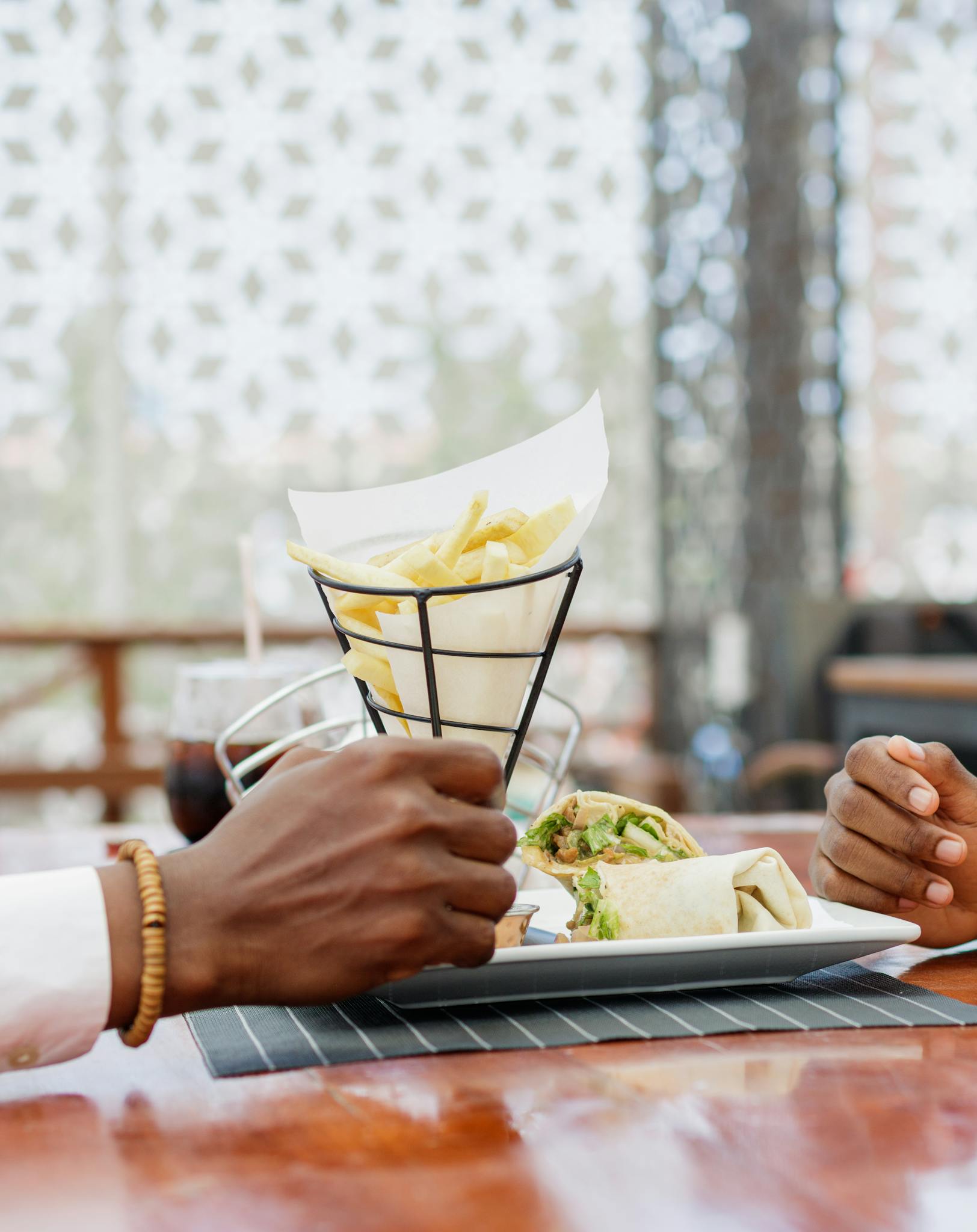 African couple dining outdoors with French fries and wrap in Accra, Ghana.
